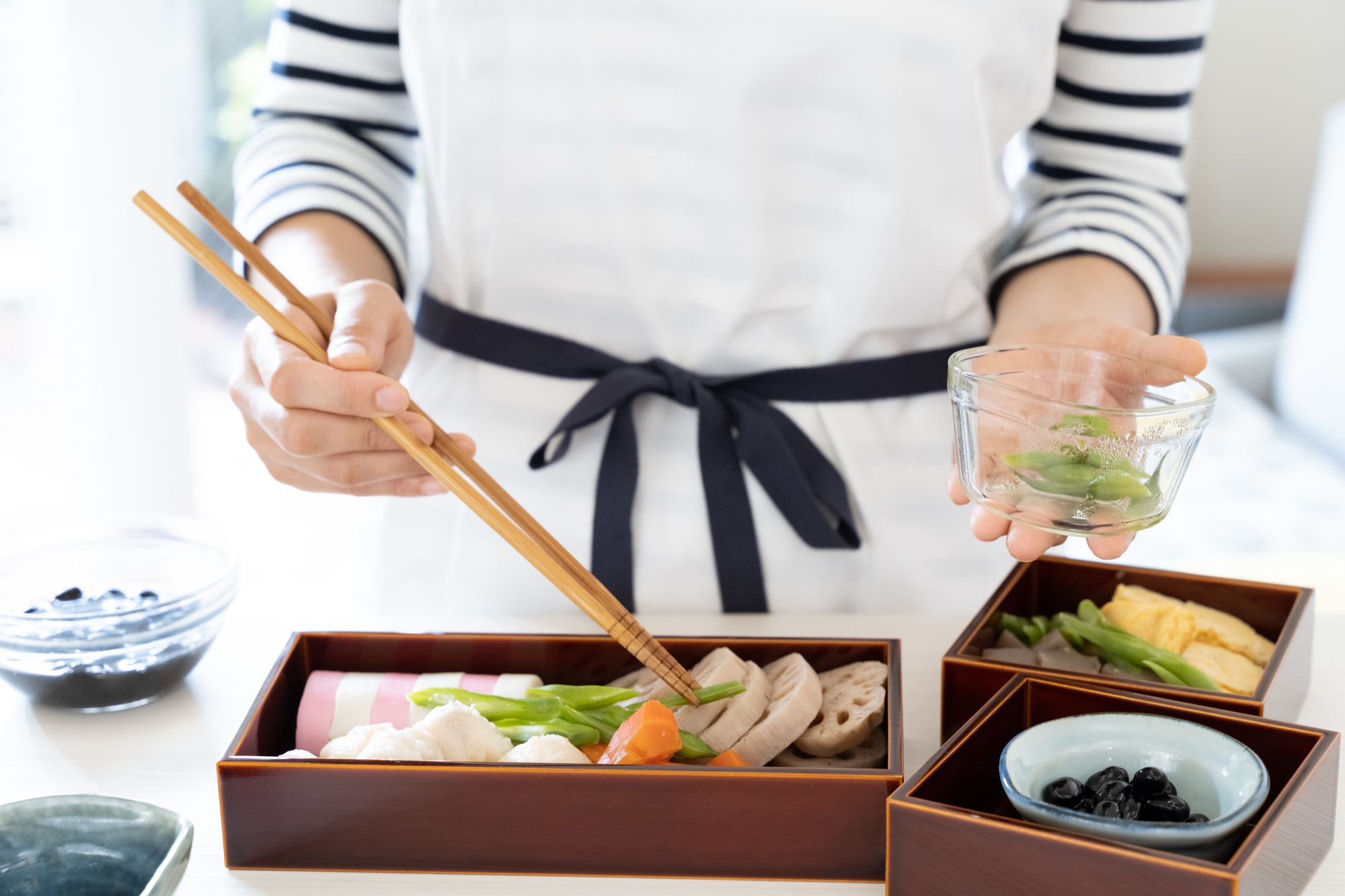 重箱におせち料理を詰めている人